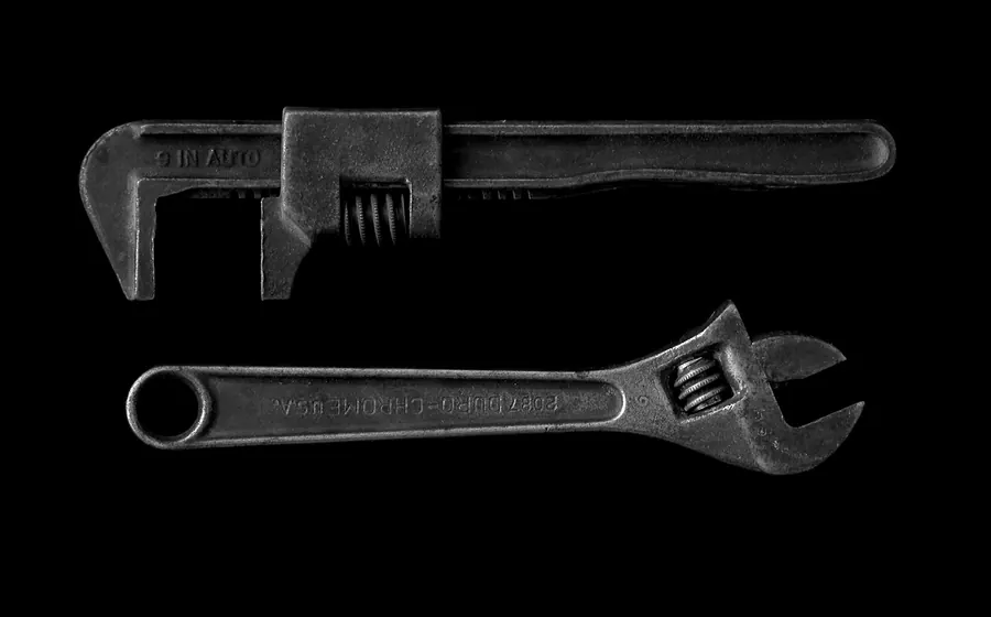 Llave para cañerías y llave inglesa sobre fondo oscuro